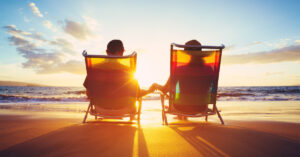 Two people holding hands in beach chairs.