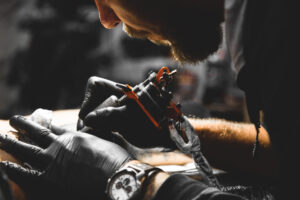 The tattoo artist creates a picture on the body of a man. close-up of tattoo machines and hands
