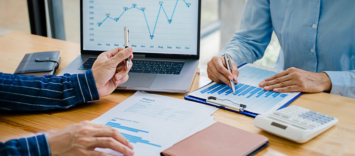 Business people discussing the charts and graphs showing the results of their successful teamwork.